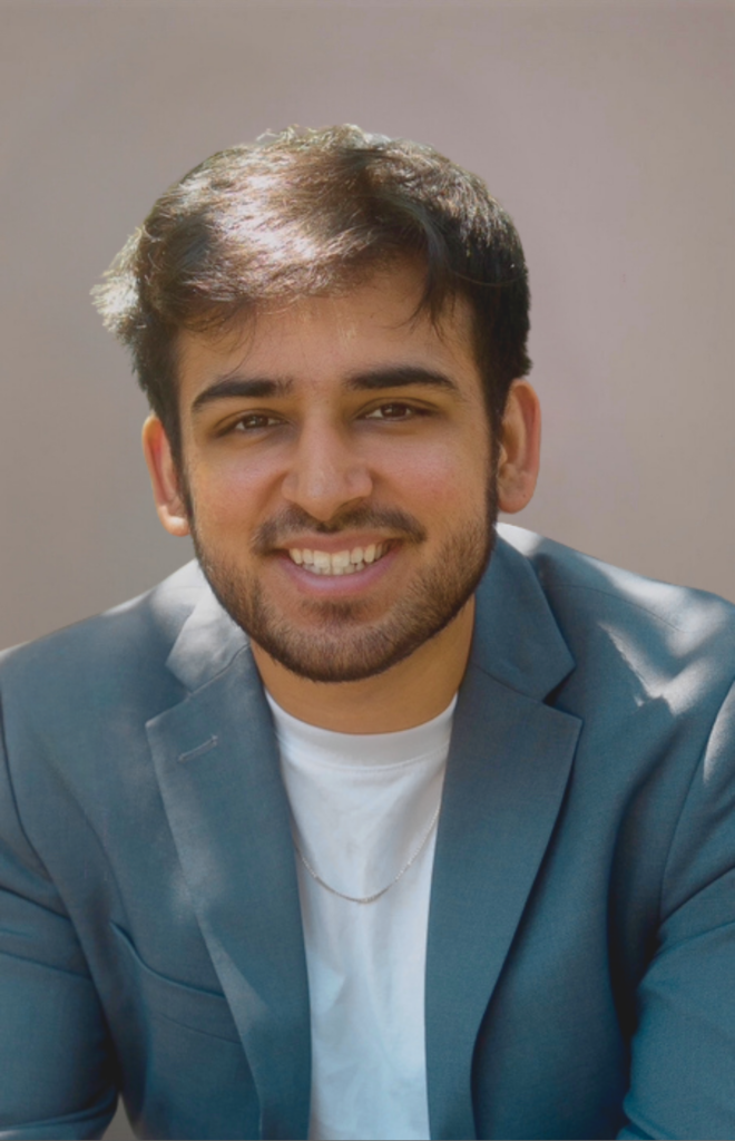 headshot of a young man smiling. wearing a jacket